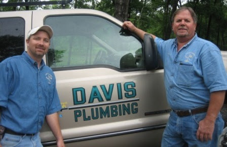 The two owners standing beside a branded work truck